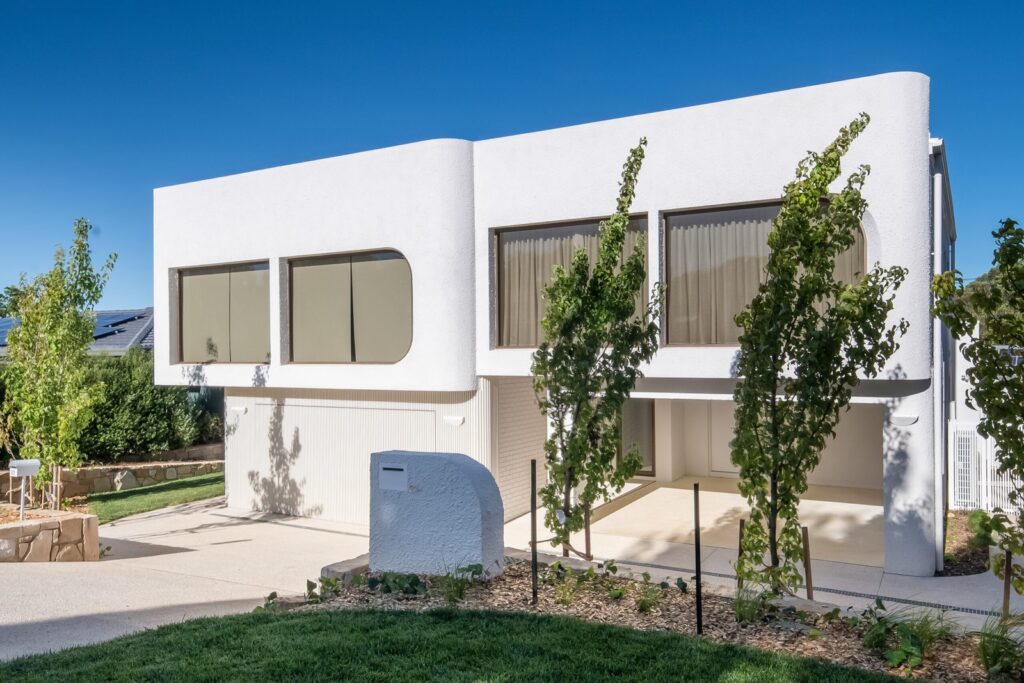 Natural bronze curved windows across the white façade of the Curtin Duplex